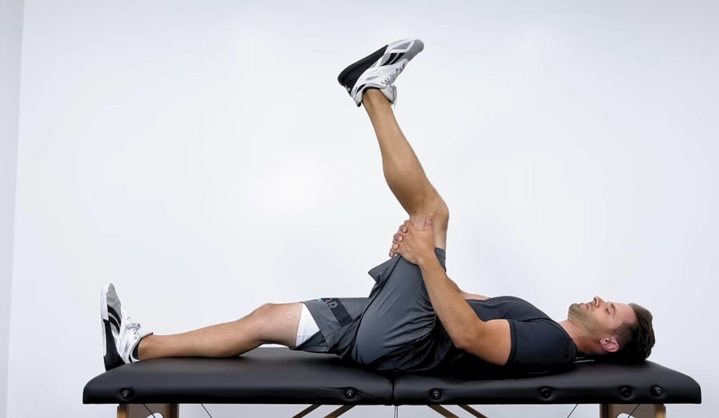 A person executing a single-leg hamstring stretch while lying down