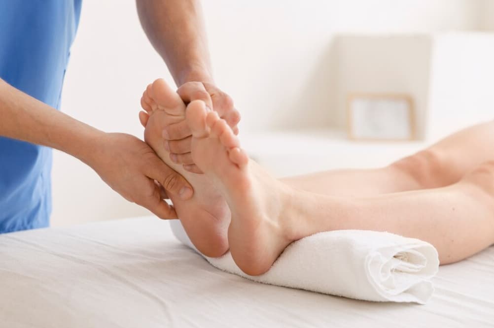 Hands of a therapist provide a foot massage to a reclining patient