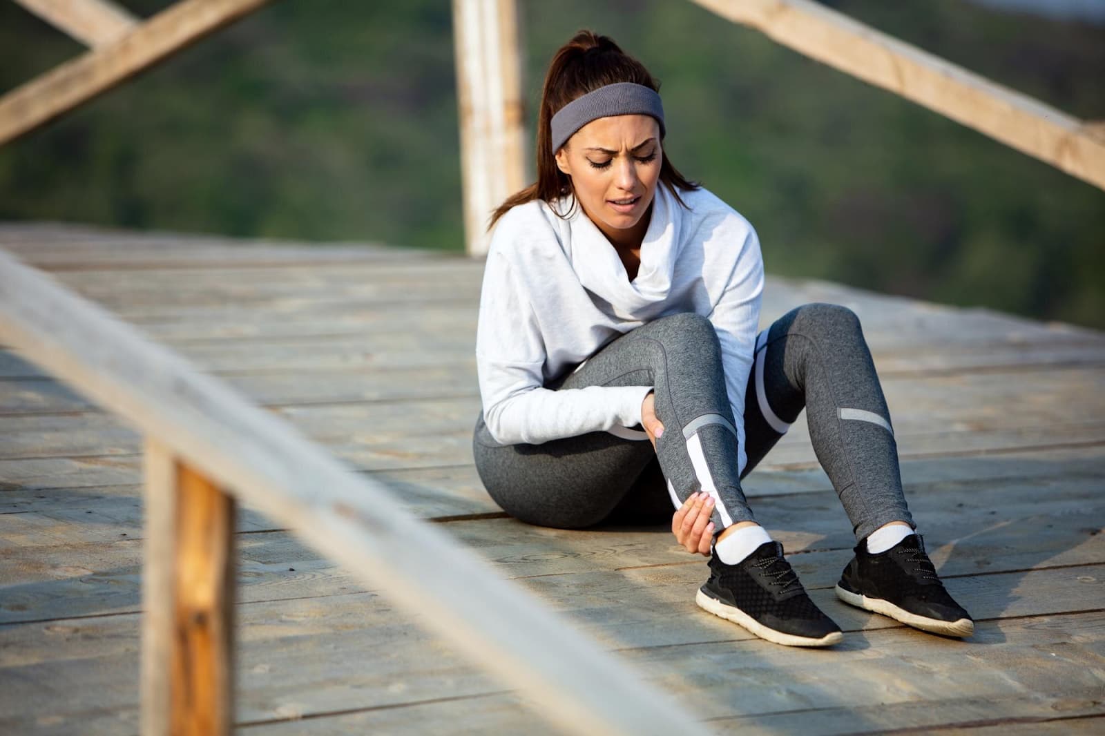 A sportswoman experiences pain in her leg while training outdoors