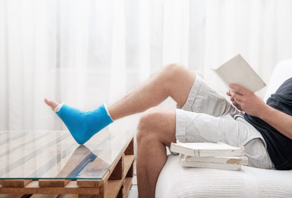 A man with a broken leg in a cast reads books