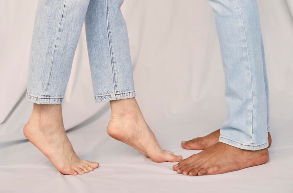 Two people showing their bare feet with one having flat arches