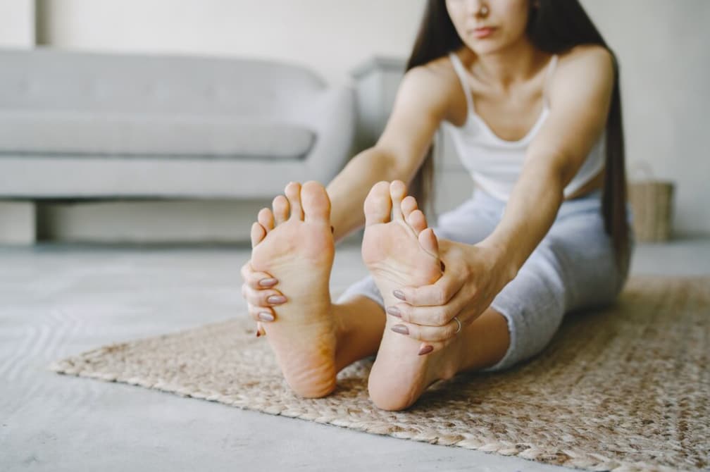 A person sitting stretching their feet towards them, revealing soles