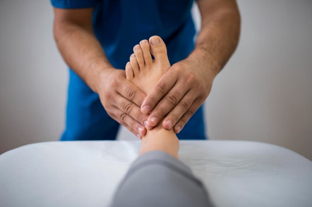 A professional examining a patient's bare feet with both hands