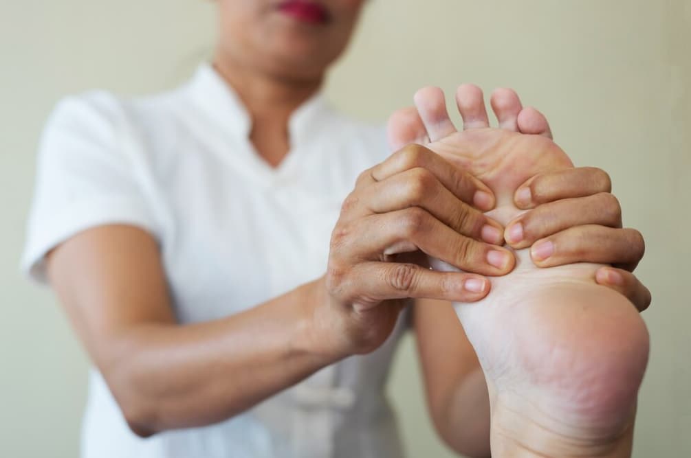 A person massages the bottom of a bare foot