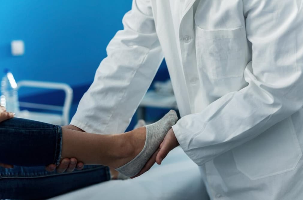 A healthcare worker holds a patient's foot in a clinic