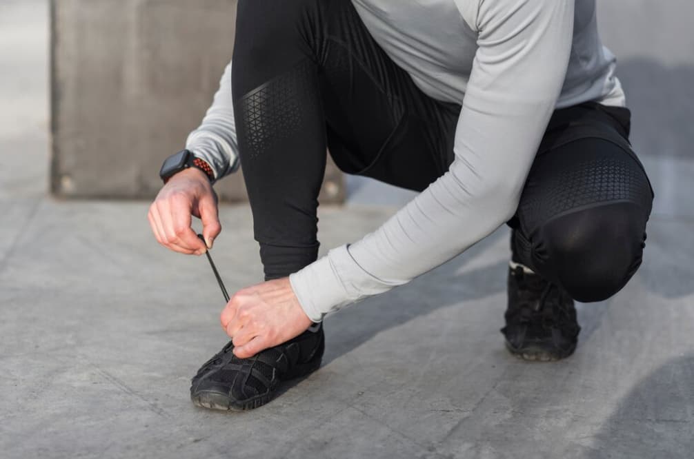 Someone ties their running shoe, prepping for exercise