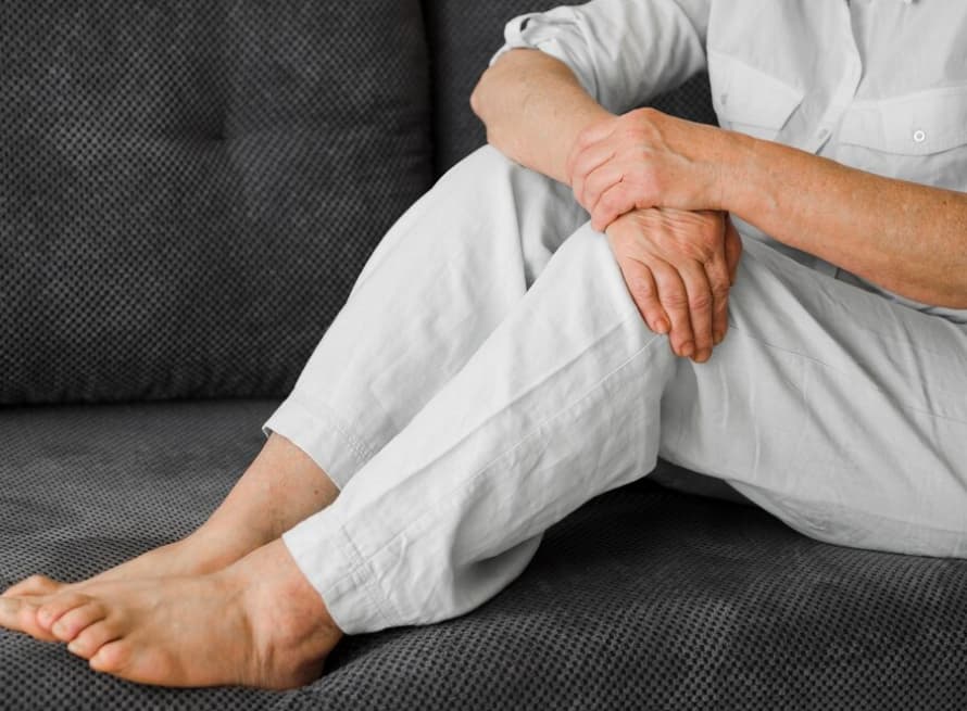 persona in a white linen suit sitting on the black sofa and holding knees